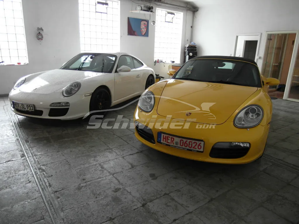Porsche 911 997, weiß, neben einem Boxster, gelb, in der Halle