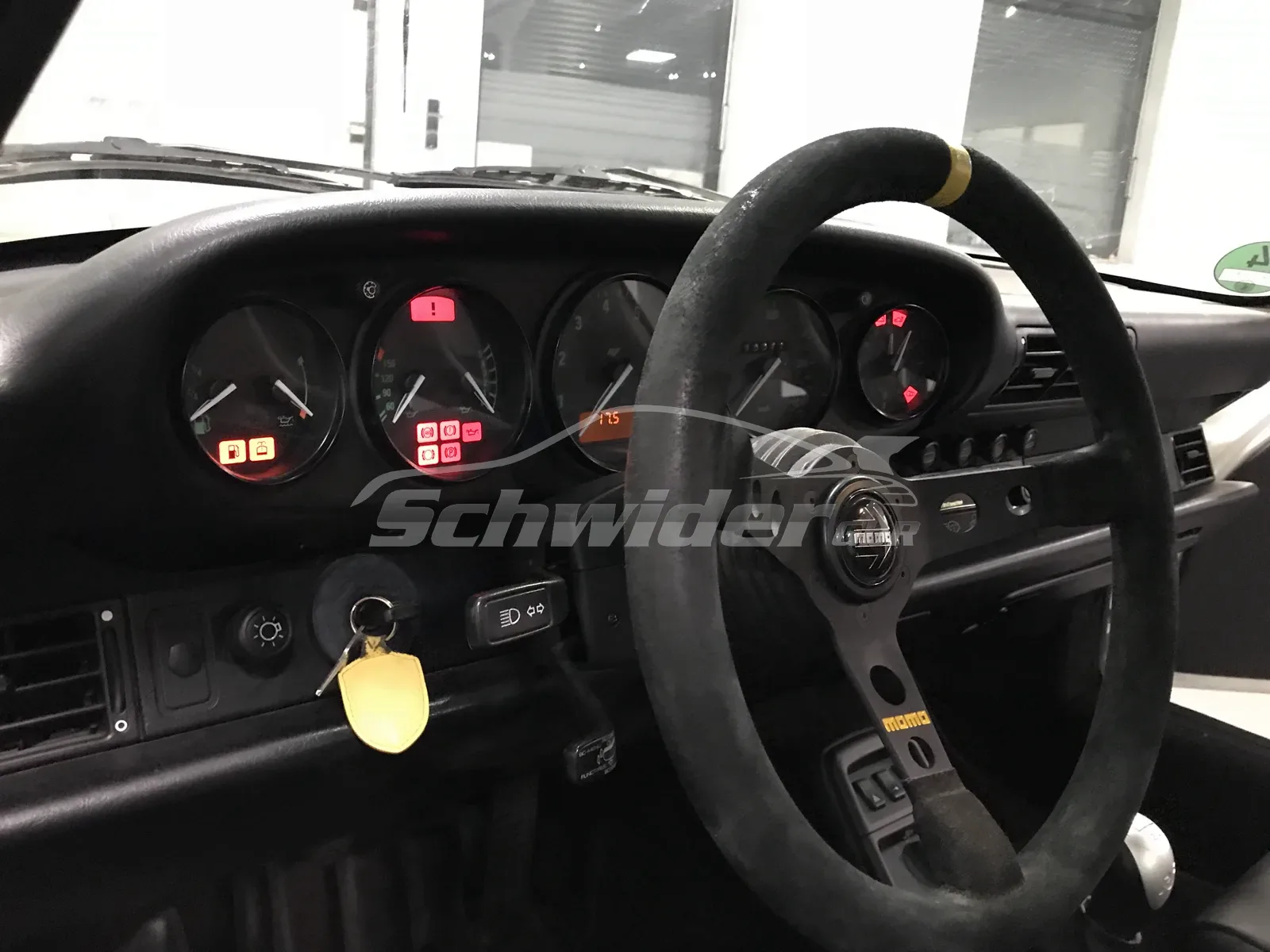 Porsche-Cockpit mit MOMO-Lenkrad und leuchtenden Kontrollleuchten — Technikprüfung in der Halle